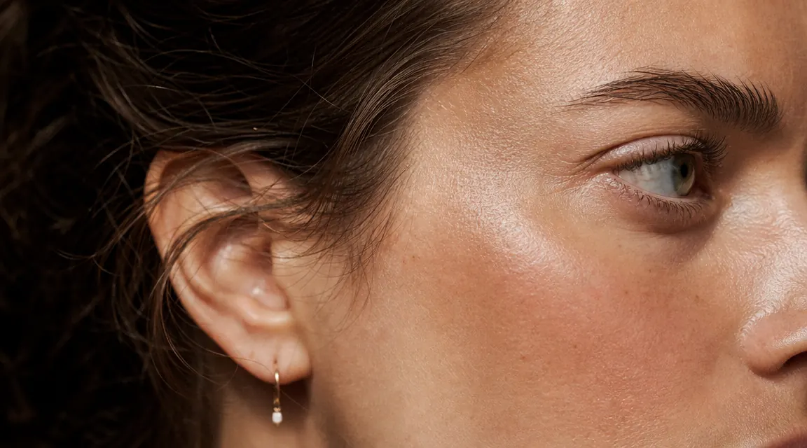 Close-up of a woman's clean, healthy skin glowing in soft natural light near a window