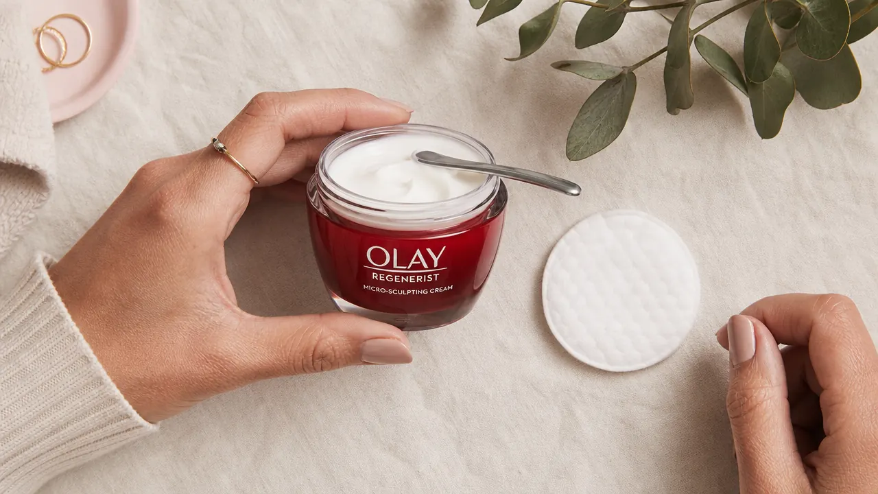 Overhead flat lay showing the Olay Regenerist jar next to a small spatula and a clean cotton round